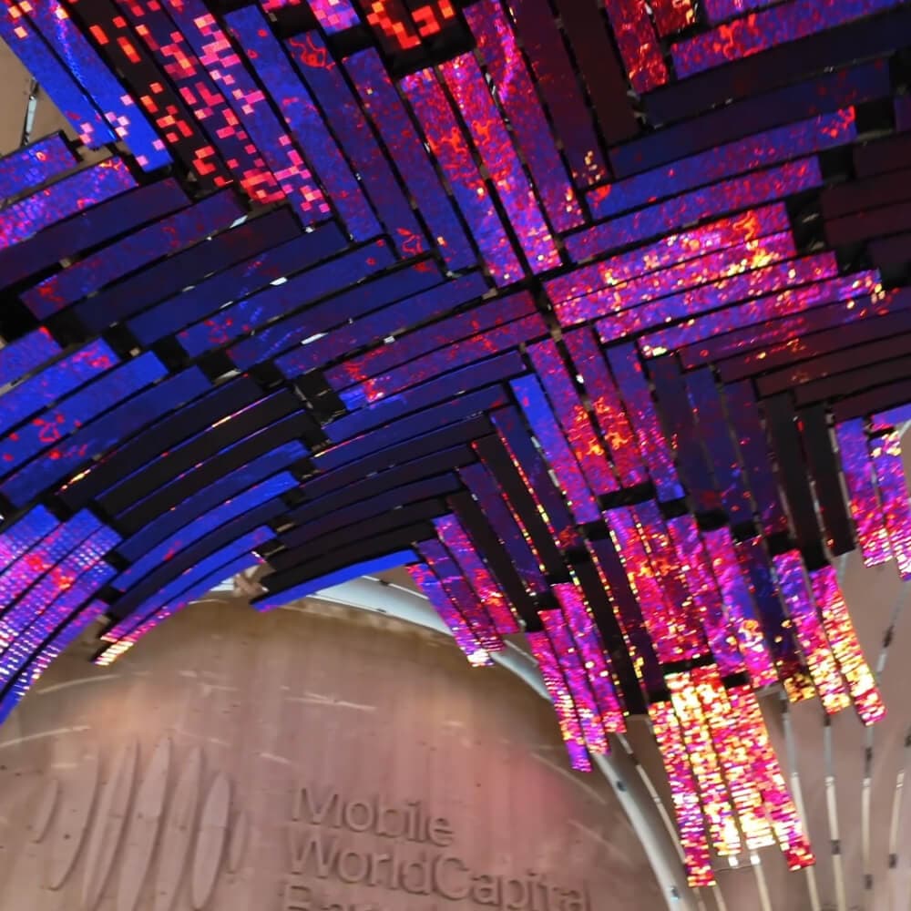 Detalle de las tiras LED del domo, en tonos violeta y rojo, con el rótulo Mobile World Capital Barcelona debajo.