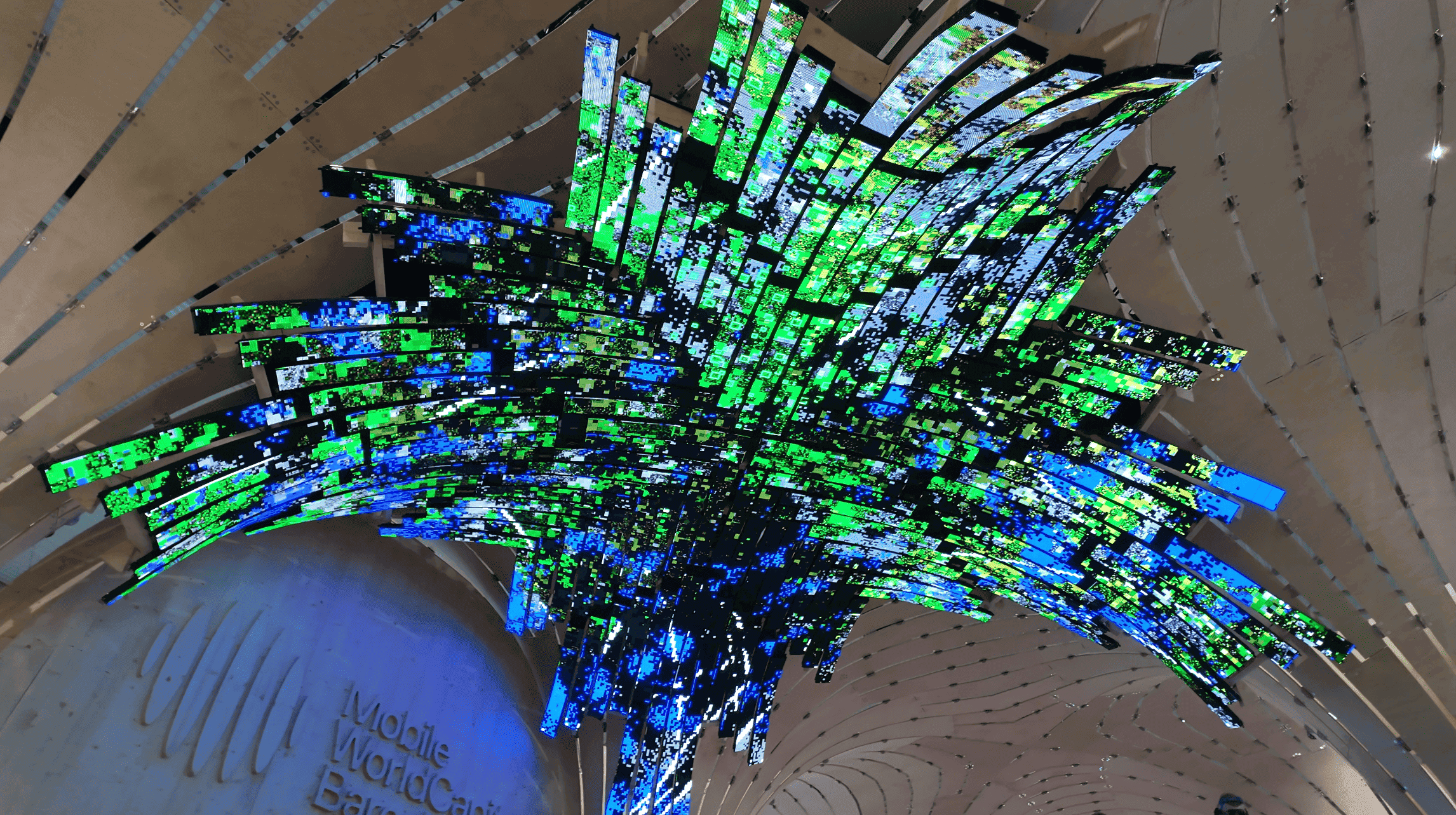 Detalle del techo LED en verdes y azules sobre el rótulo Mobile World Capital Barcelona.